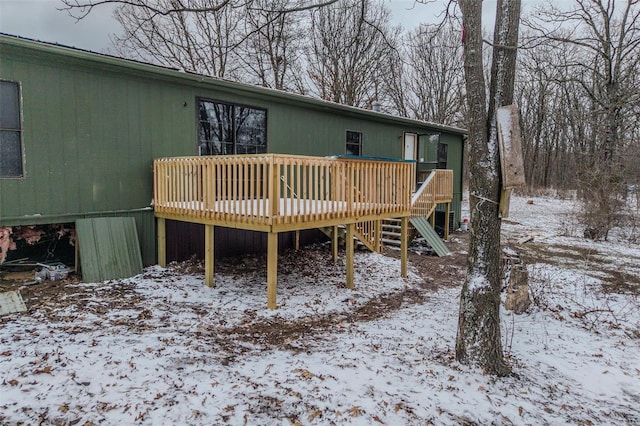 snow covered back of property with a deck