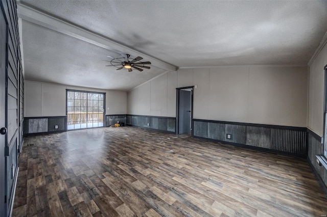 unfurnished living room with a wainscoted wall, lofted ceiling with beams, a ceiling fan, a textured ceiling, and wood finished floors