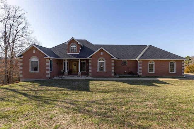 view of front of property featuring brick siding, a shingled roof, and a front lawn