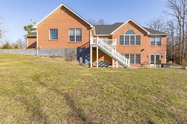 back of house featuring brick siding, a lawn, stairs, and a patio area