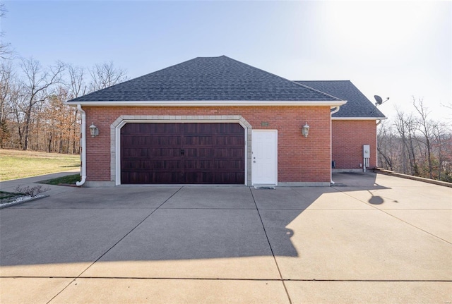 view of side of property with brick siding, concrete driveway, and a shingled roof