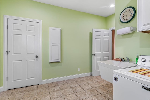 clothes washing area featuring light tile patterned floors, cabinet space, washer / clothes dryer, and baseboards