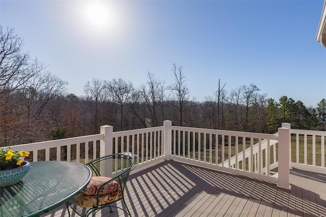 wooden terrace with outdoor dining area and a view of trees