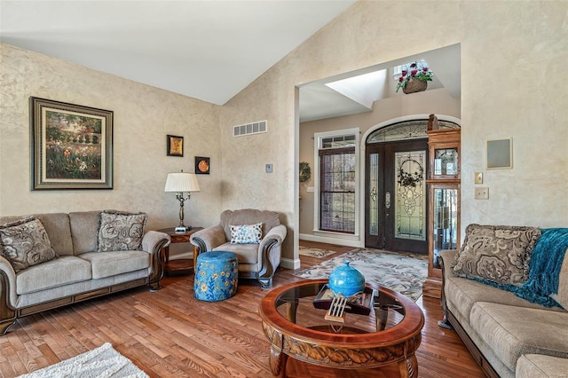 living room featuring visible vents, baseboards, high vaulted ceiling, and wood finished floors