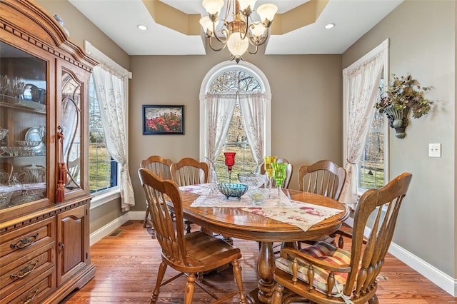 dining space featuring a notable chandelier, a healthy amount of sunlight, baseboards, and light wood-type flooring