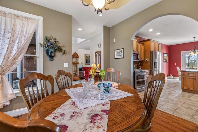 dining space with recessed lighting, baseboards, arched walkways, and an inviting chandelier