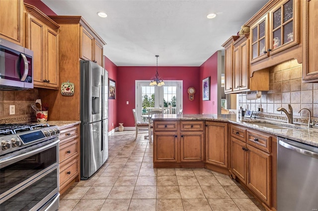 kitchen featuring brown cabinets, a sink, stainless steel appliances, a peninsula, and light tile patterned flooring