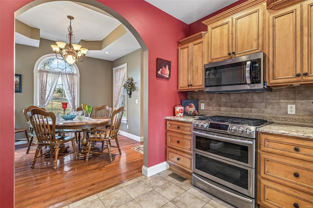 kitchen featuring decorative backsplash, visible vents, arched walkways, and appliances with stainless steel finishes