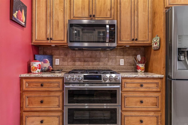 kitchen with decorative backsplash, brown cabinets, and appliances with stainless steel finishes