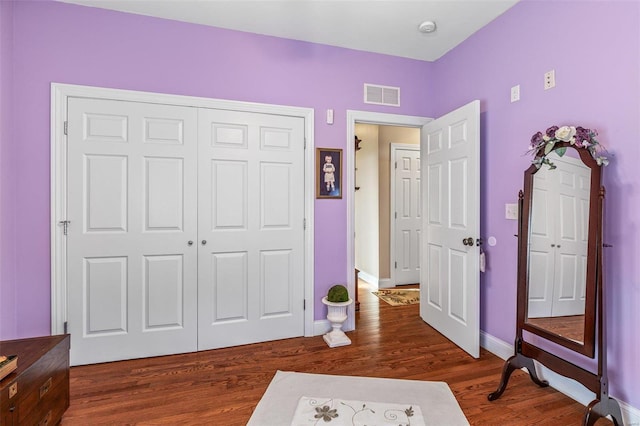 bedroom featuring a closet, visible vents, baseboards, and wood finished floors