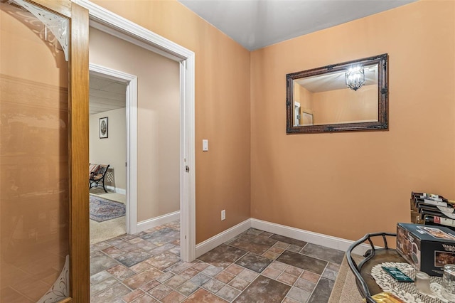 hallway featuring stone finish flooring and baseboards