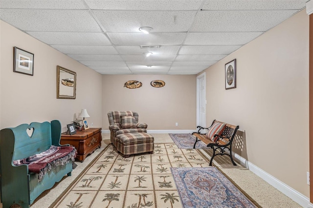 living area with a drop ceiling, visible vents, and baseboards