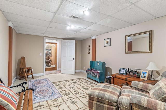 living room featuring a paneled ceiling, baseboards, visible vents, and light carpet