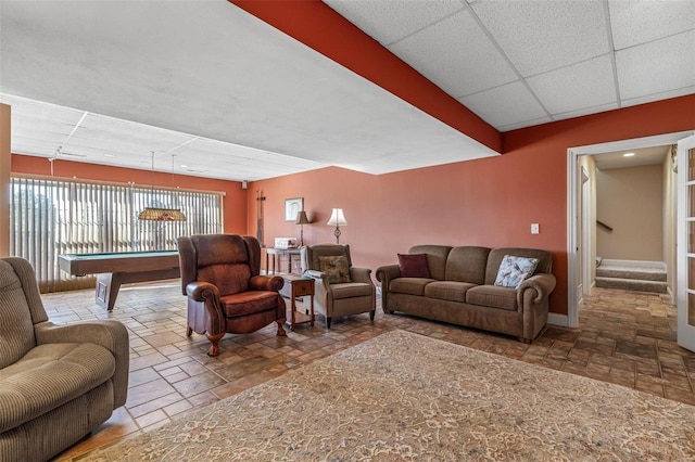 living area featuring billiards, stone tile floors, a paneled ceiling, baseboards, and stairs