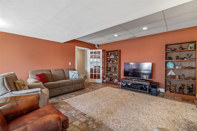 living area featuring recessed lighting, a drop ceiling, stone finish floor, and baseboards