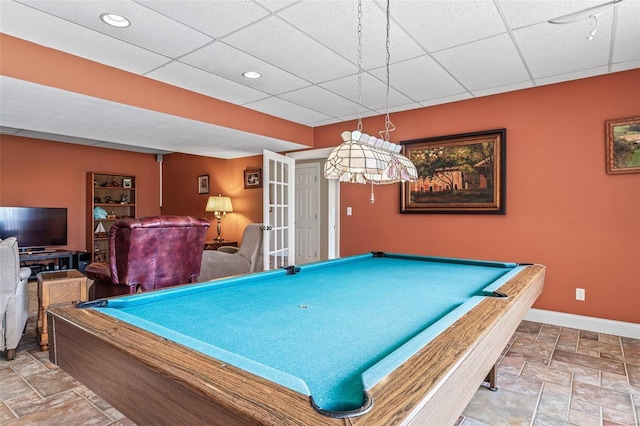 recreation room with pool table, stone finish floor, a paneled ceiling, and baseboards