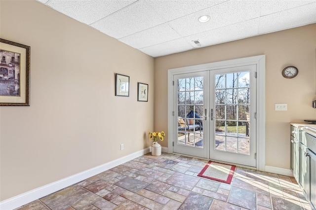 doorway to outside with visible vents, baseboards, french doors, stone finish floor, and a paneled ceiling