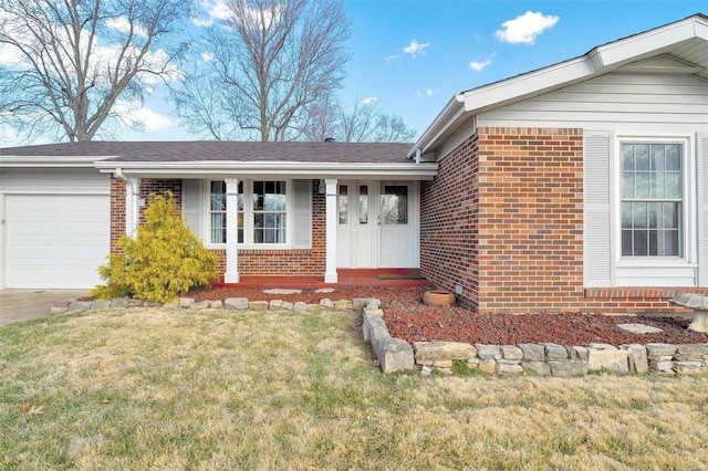 property entrance featuring a yard, brick siding, concrete driveway, and an attached garage