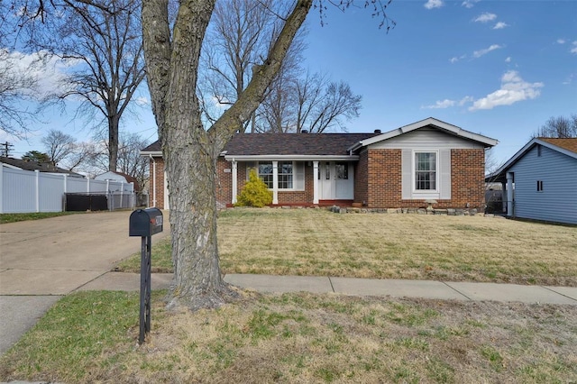 view of front of property with a front lawn, fence, brick siding, and driveway