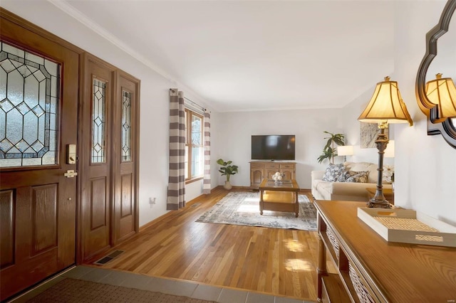 entryway with visible vents, crown molding, baseboards, and wood finished floors