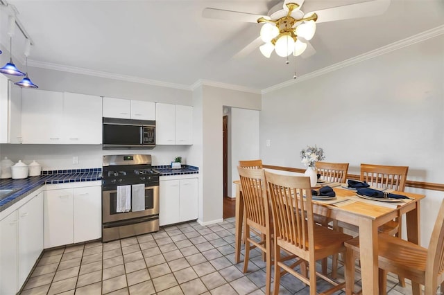 kitchen with white cabinets, gas stove, black microwave, and ornamental molding