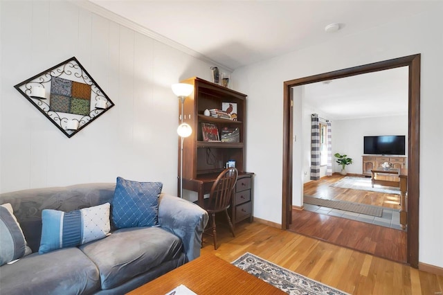 living area with crown molding, baseboards, and wood finished floors