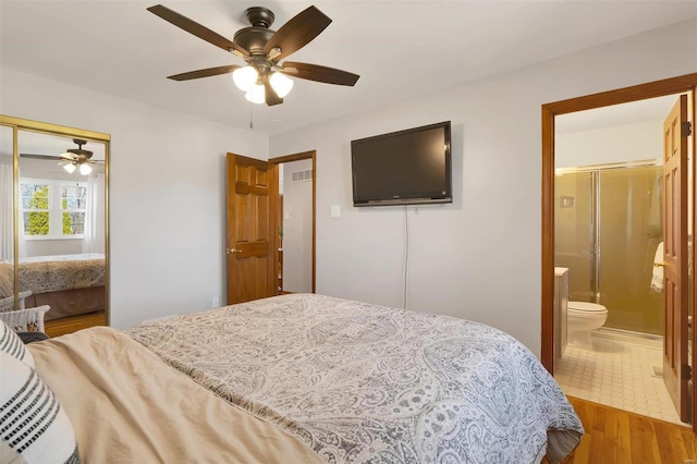 bedroom with a ceiling fan, visible vents, wood finished floors, a closet, and ensuite bathroom