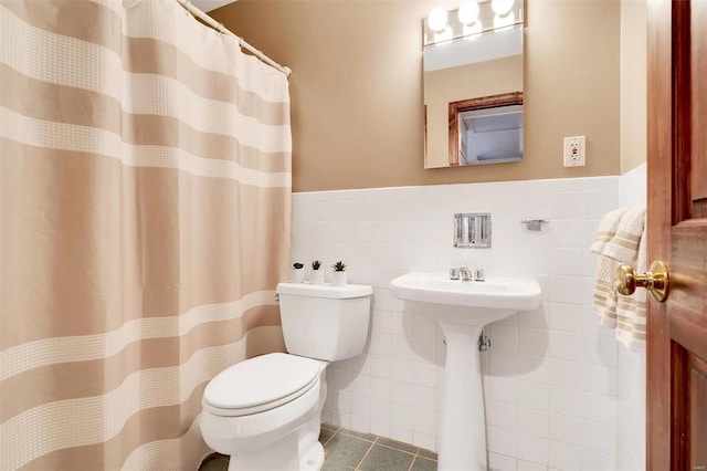 bathroom with tile patterned flooring, tile walls, toilet, and wainscoting