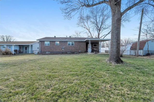 rear view of property with a yard, brick siding, and fence