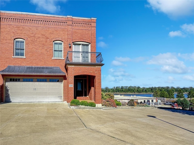 townhome / multi-family property featuring a balcony, a garage, concrete driveway, and brick siding