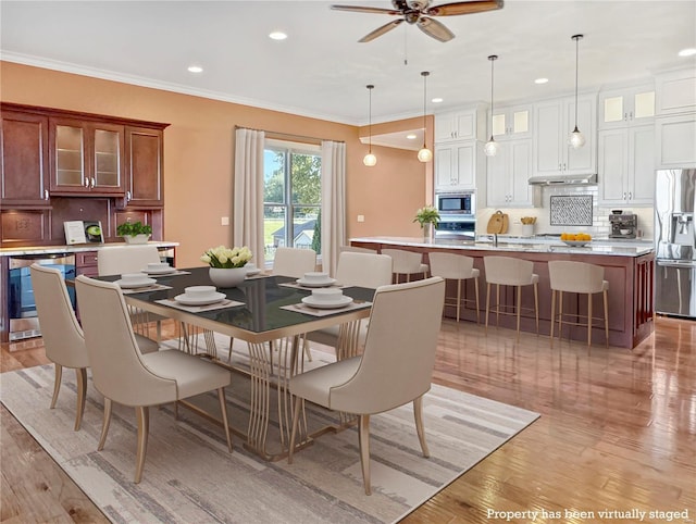 dining space with ornamental molding, light wood-type flooring, recessed lighting, and wine cooler