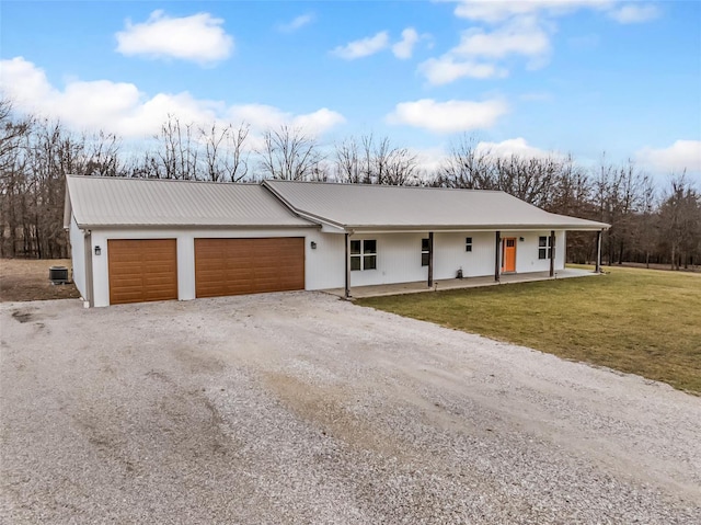 view of front facade featuring gravel driveway, a front yard, a garage, and metal roof