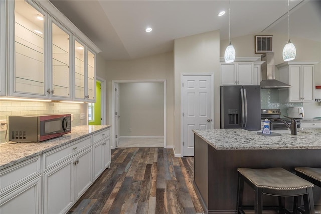 kitchen featuring vaulted ceiling, wall chimney exhaust hood, visible vents, and stainless steel appliances