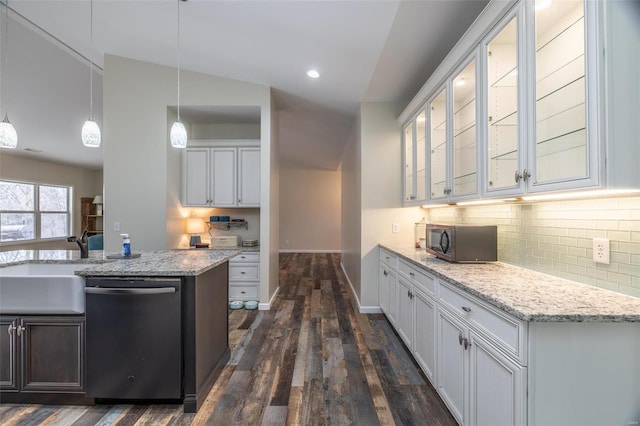 kitchen featuring dishwashing machine, dark wood finished floors, a sink, stainless steel microwave, and tasteful backsplash