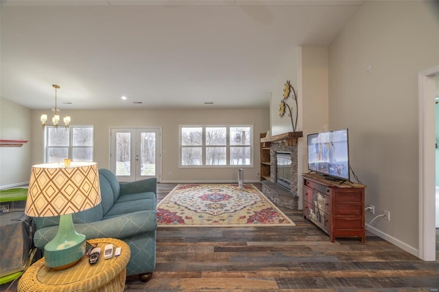 living room featuring wood finished floors, french doors, an inviting chandelier, a fireplace, and baseboards