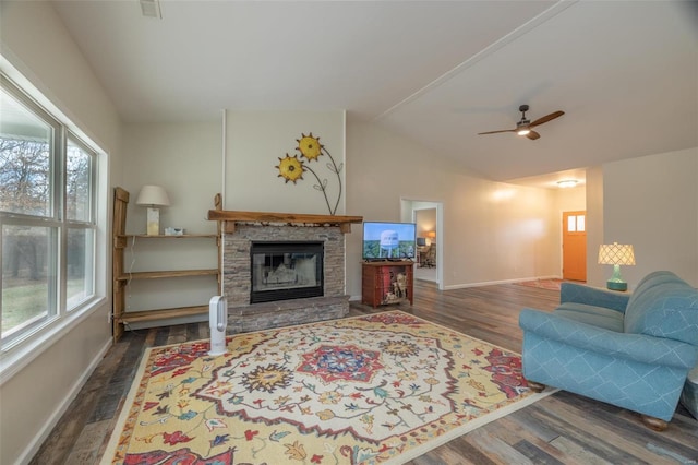 living room featuring plenty of natural light, a stone fireplace, wood finished floors, and vaulted ceiling