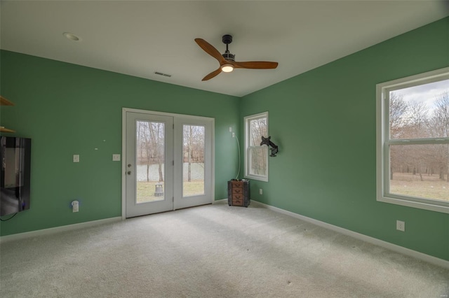 carpeted spare room with visible vents, ceiling fan, and baseboards