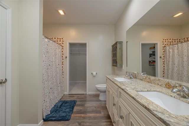 full bath with a sink, toilet, wood finished floors, and double vanity