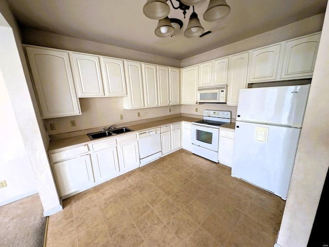 kitchen with white appliances, a notable chandelier, white cabinets, and a sink