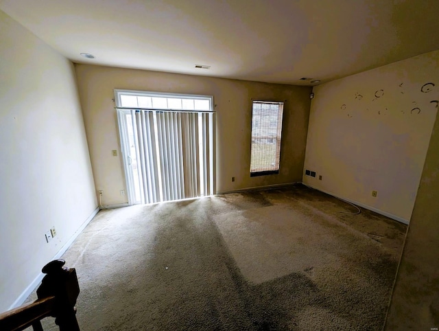 carpeted spare room featuring visible vents and baseboards