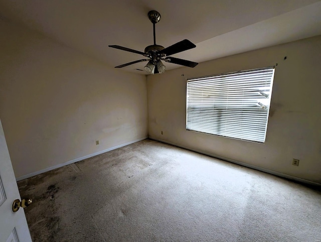 carpeted empty room featuring ceiling fan and baseboards