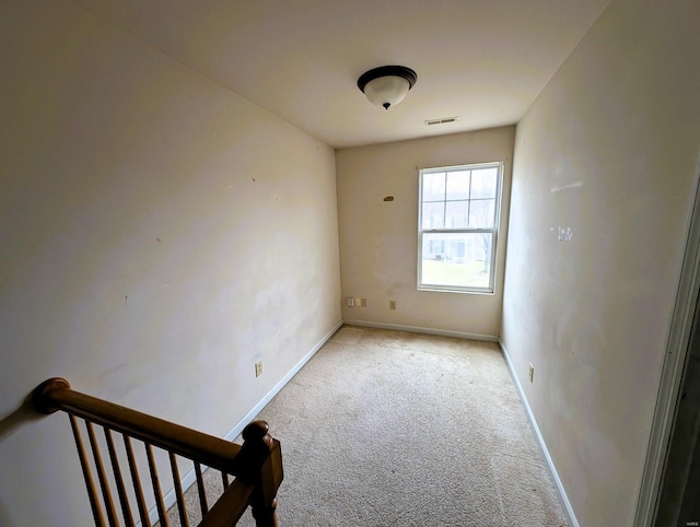 unfurnished room with visible vents, baseboards, and light colored carpet