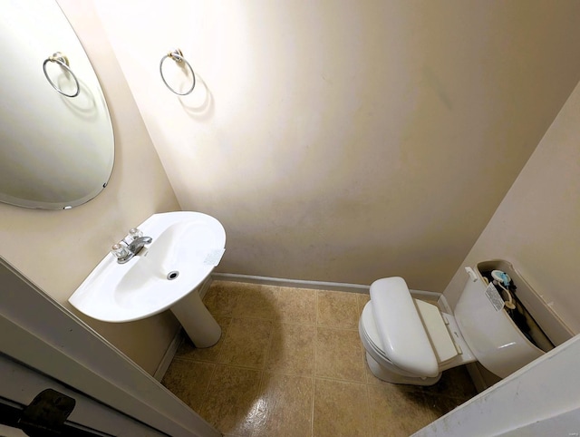 half bathroom featuring baseboards, a sink, toilet, and tile patterned floors