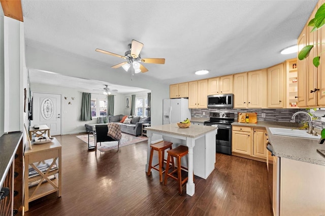 kitchen with a sink, open floor plan, a center island, appliances with stainless steel finishes, and decorative backsplash