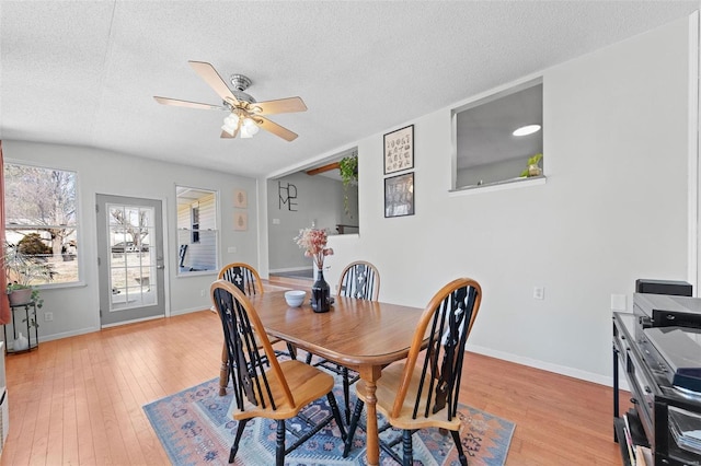 dining area featuring baseboards, a textured ceiling, and light wood finished floors