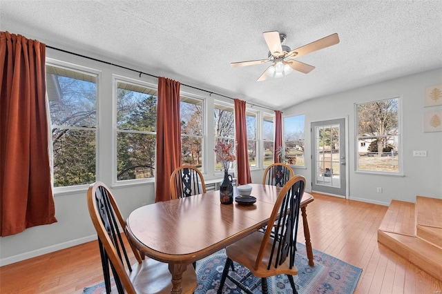 dining area with light wood-type flooring, baseboards, and a textured ceiling