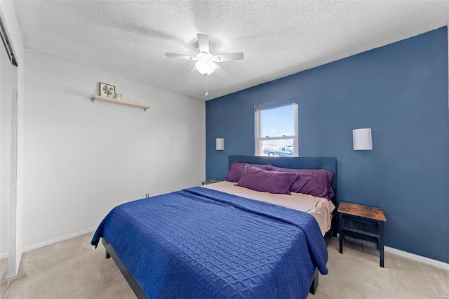 carpeted bedroom with a textured ceiling, a ceiling fan, and baseboards