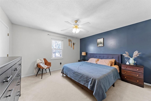 bedroom featuring light carpet, a textured ceiling, a ceiling fan, and baseboards