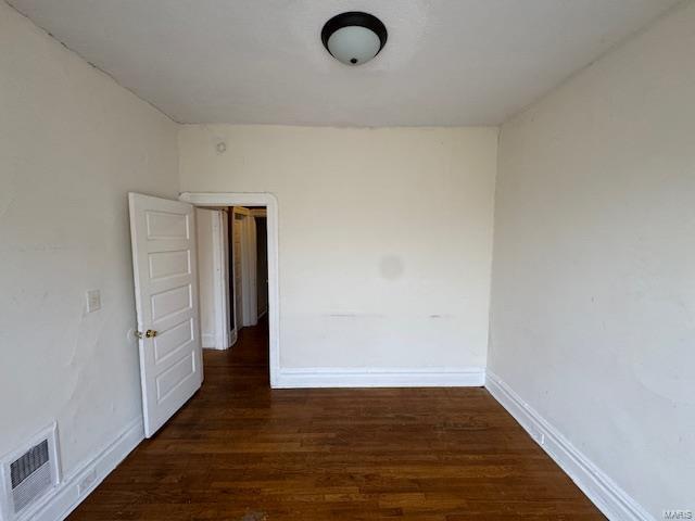 empty room with visible vents, baseboards, and wood finished floors