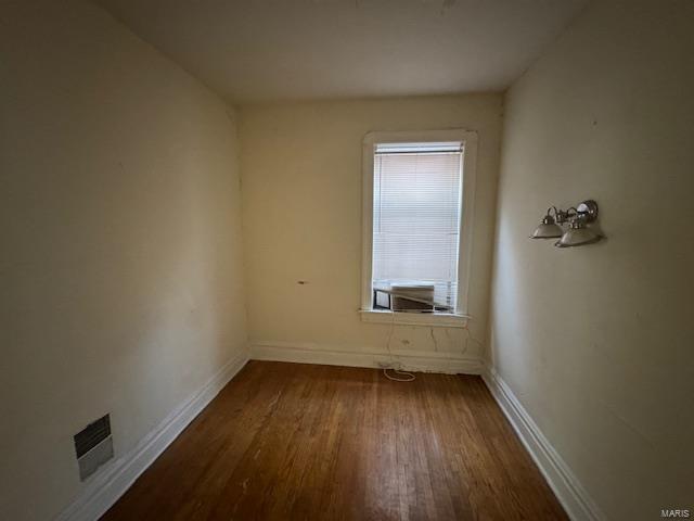 spare room featuring cooling unit, dark wood-style flooring, visible vents, and baseboards